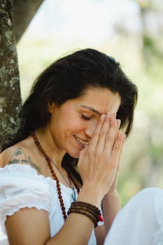 Gratitude and Manifestation - A peaceful woman with hands clasped in prayer, meditating outdoors on a sunny day.