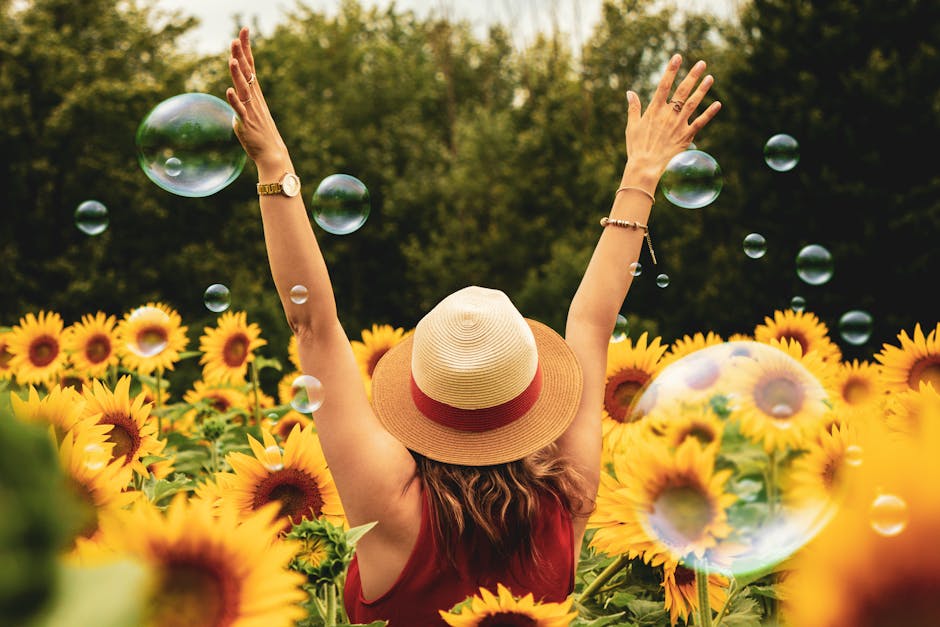 A joyful woman in a sunflower field with bubbles, expressing happiness on a summer day.