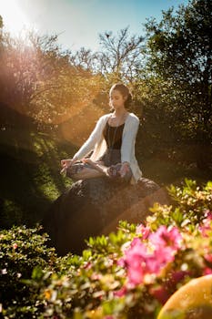 How to Connect to your Spirit Guides - Woman in tranquil meditation pose outdoors, bathed in sunlight, surrounded by lush greenery.