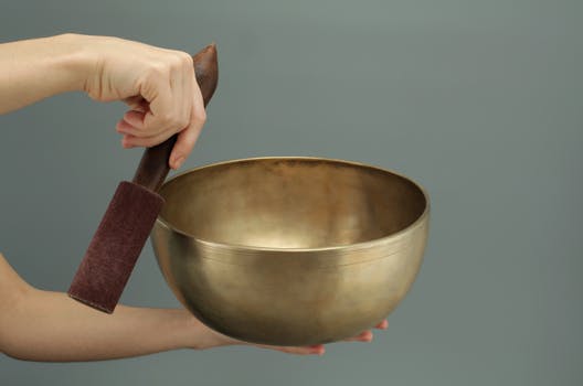 How to remove negative energy -Close-up of a hand holding a Tibetan singing bowl used for meditation and relaxation.