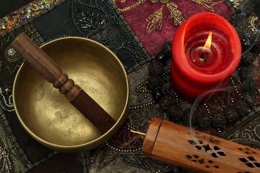 How to raise your vibration - Close-up of a Tibetan singing bowl, candle, and incense on colorful fabric, creating a serene ambiance.