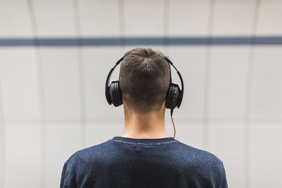 Back view of a man listening to music with headphones indoors.