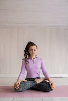 Manifestation Visualization - Woman practicing yoga meditation indoors on a pink mat, focusing on relaxation and mindfulness.