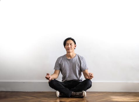 Manifesting Financial Abundance - Man practicing meditation indoors on a wooden floor, promoting relaxation and mindfulness.