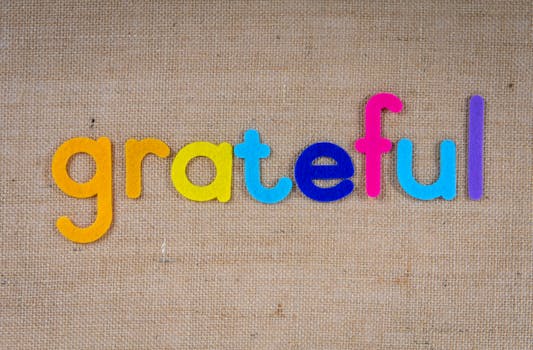 Gratitude and Manifestation - Colorful felt letters forming the word 'grateful' on a burlap background.