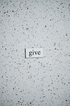 7 Laws of Attraction - High-angle photo of the word 'give' on a speckled surface, emphasizing simplicity and minimalism.