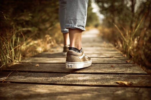 How to unblock chakras - Person wearing sneakers walking on a wooden path in a sunlit park.