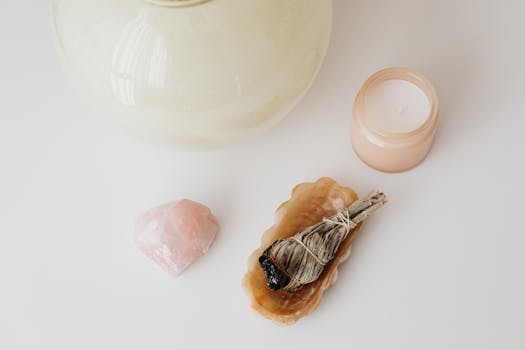 Manifesting with Crystals - Serene flat lay of a candle, smudge stick, and crystal perfect for relaxation and spirituality.