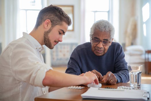 12 Laws of the Universe - A young volunteer helps an elderly man manage his medication at a nursing home.