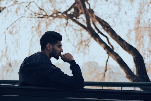 How to raise your vibration - Man in deep thought sitting on a bench in a serene autumn park setting.