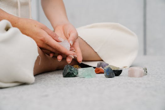 How to unblock chakras - Close-up of hands holding healing crystals on a soft surface indoors, symbolizing spirituality and mindfulness.