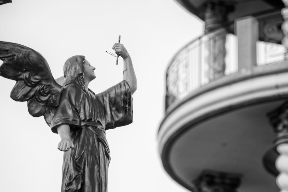 Monochrome image of an angel statue with a nearby architectural feature, capturing serene elegance.