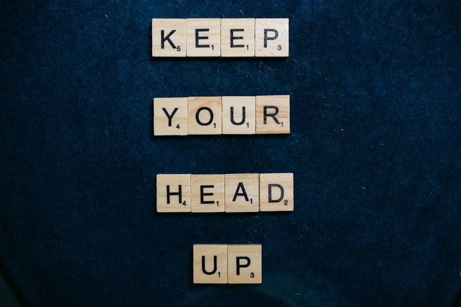 Manifestation Challenges And Strategies To Overcome Them Inspirational message 'Keep Your Head Up' in Scrabble tiles on a dark blue background.